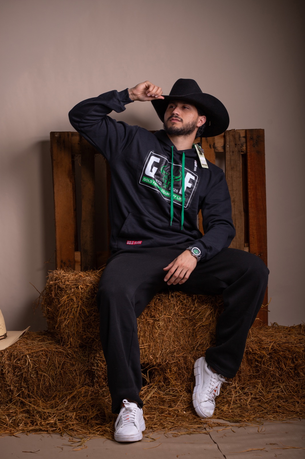 Jhonatan sentado em pose editorial usando moletom preto
